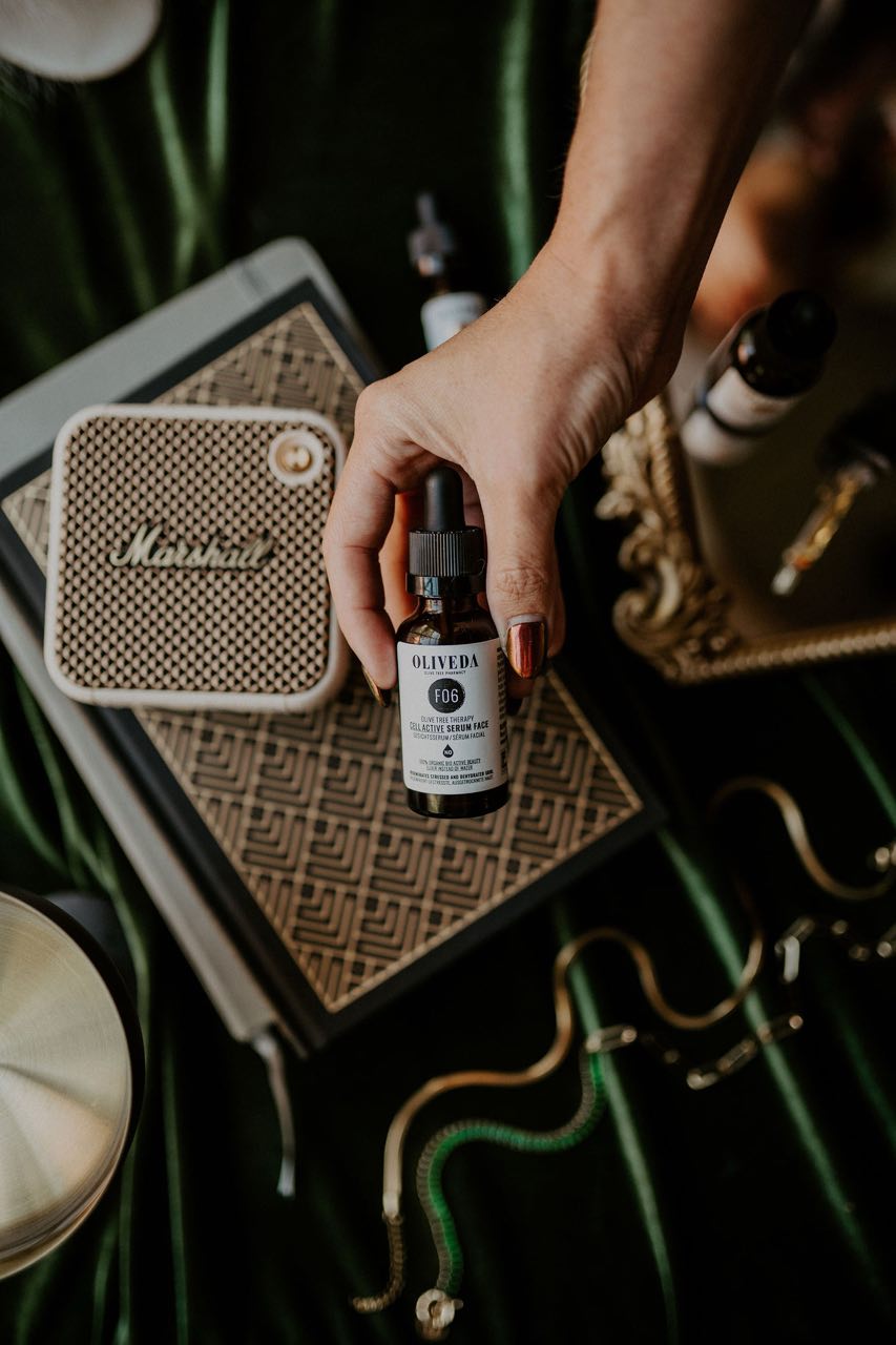 Oliveda serum styled against deep green fabric