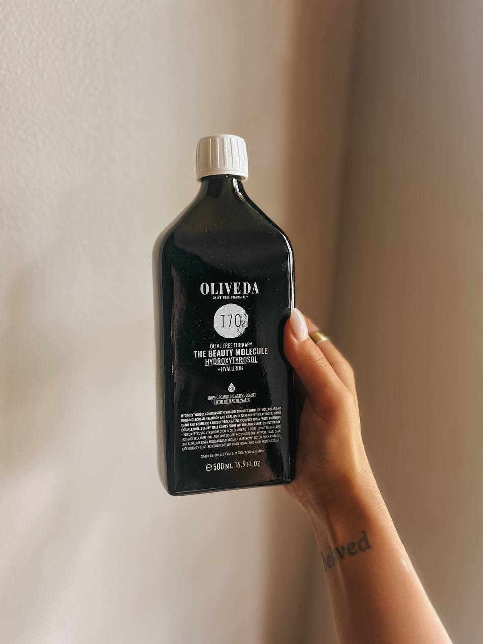 Hand holding an Oliveda I70 bottle in warm light